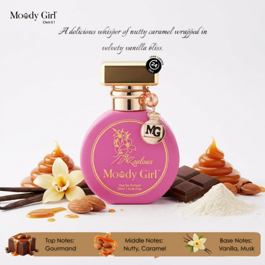 Pink perfume bottle with gold accents labeled 'Moody Girl' surrounded by vanilla beans, almonds, and chocolate on a white background.