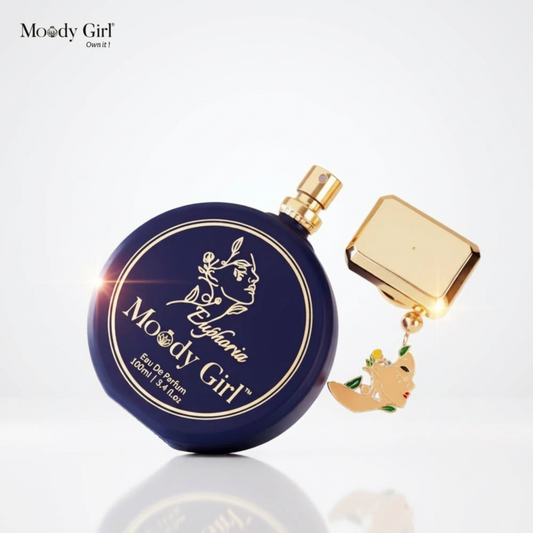 Perfume bottle labeled 'Moody Girl' with gold cap on a white background with purple flowers.