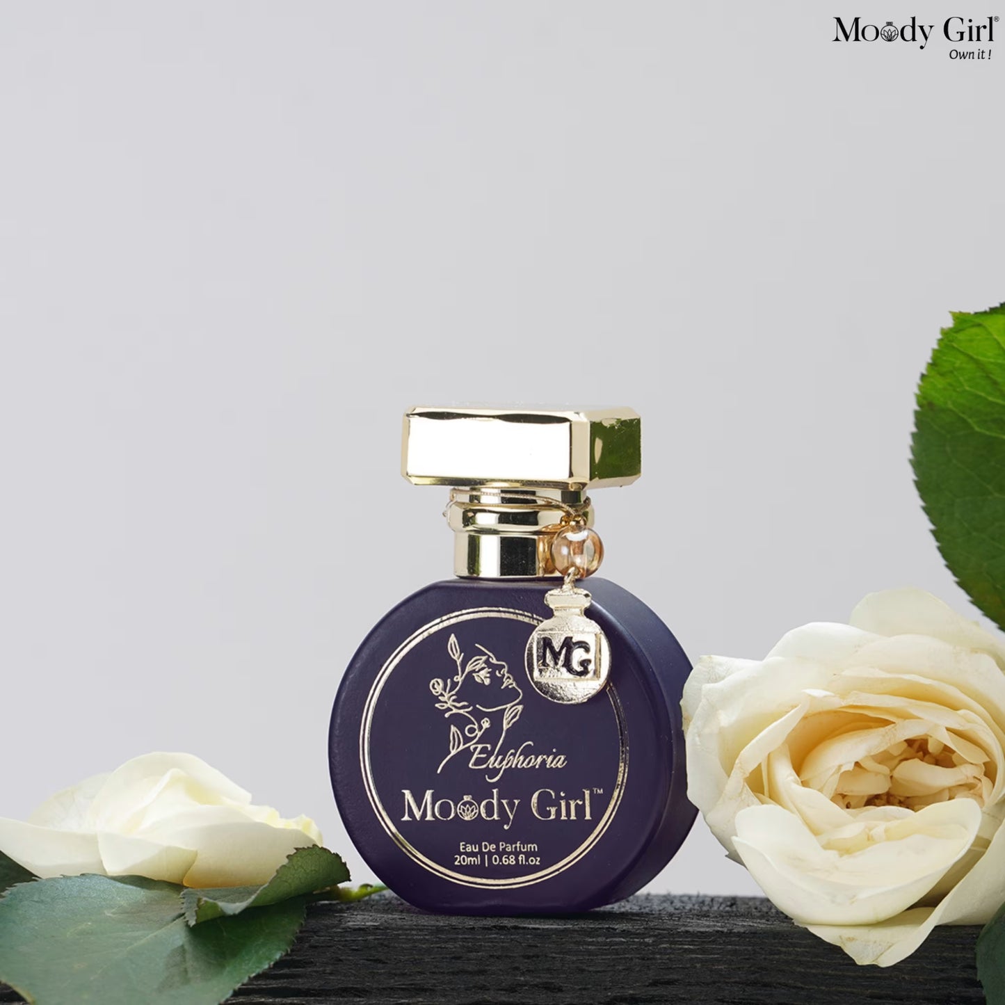 Perfume bottle labeled 'Moody Girl' with white roses on a light gray background
