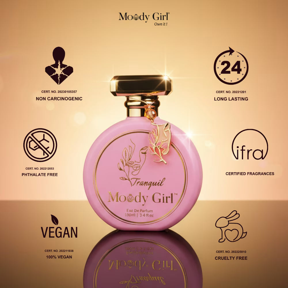 Pink perfume bottle with gold accents on a reflective surface, featuring Moody Girl branding and certification logos.