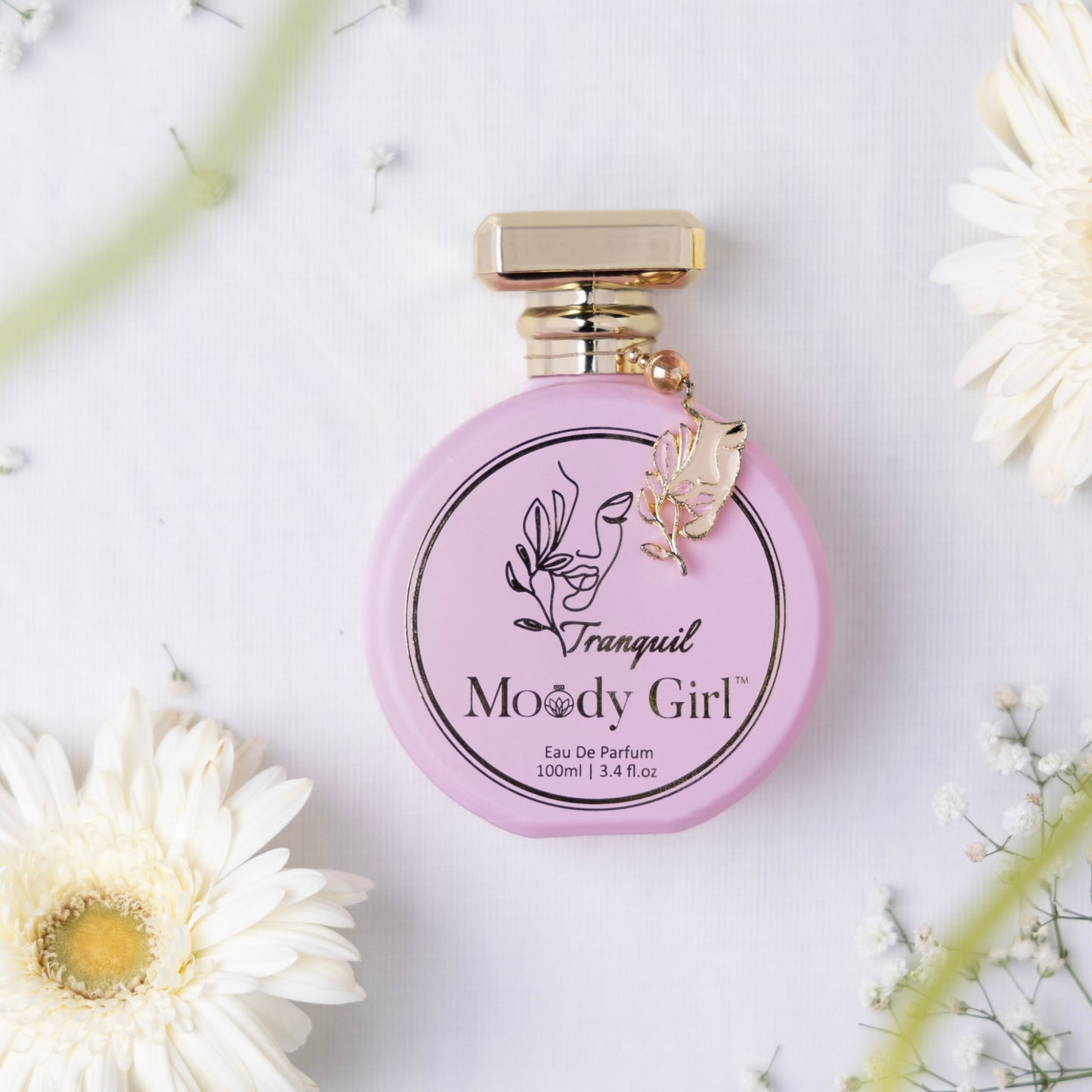 Tranquil 100ml Pink perfume bottle with gold cap on a white background with flowers