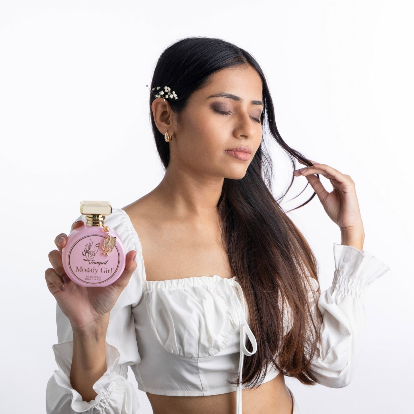 Woman holding a Moody Girl Tranquil 100ml pink perfume bottle with a white background