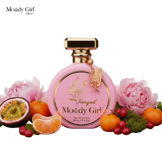 Pink perfume bottle with gold accents surrounded by flowers and fruits on a white background, featuring the brand 'Moody Girl'.