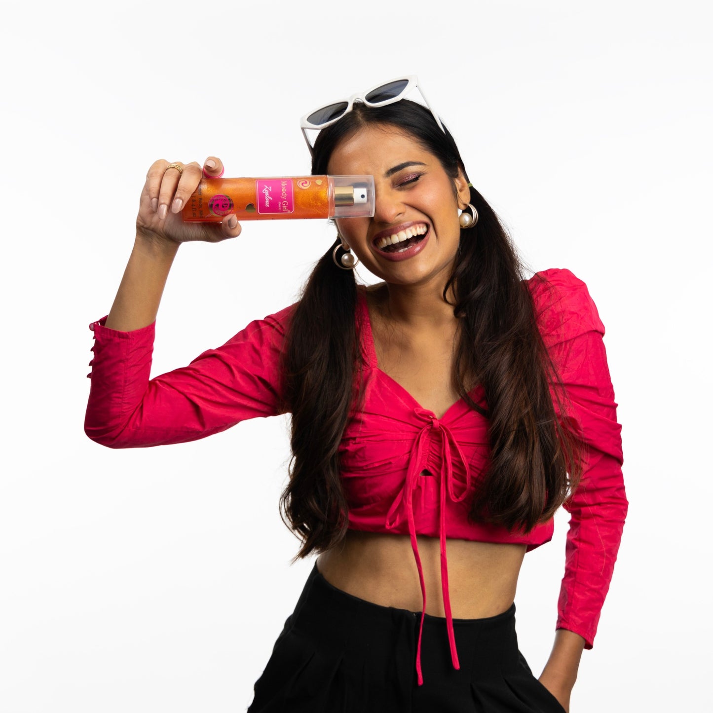 Woman in a pink top holding a Moody Girl Shimmer Body Mist product with a white background