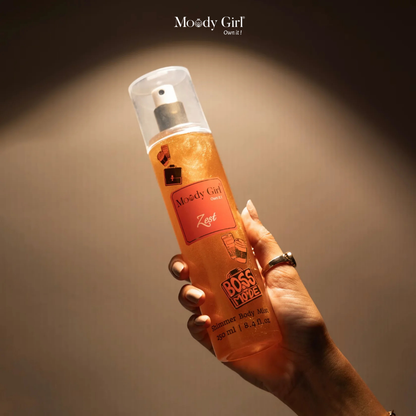 Hand holding a bottle of 'Boss Mode' body mist by Moody Girl against a dark background