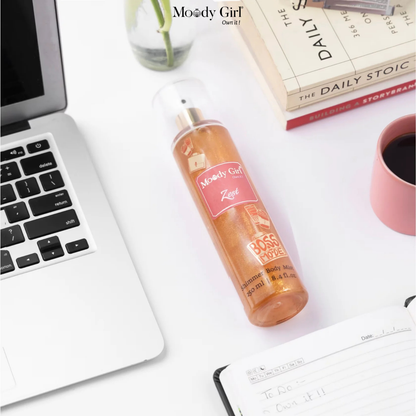 Laptop, bottle of 'Moody Girl' product, and books on a desk.