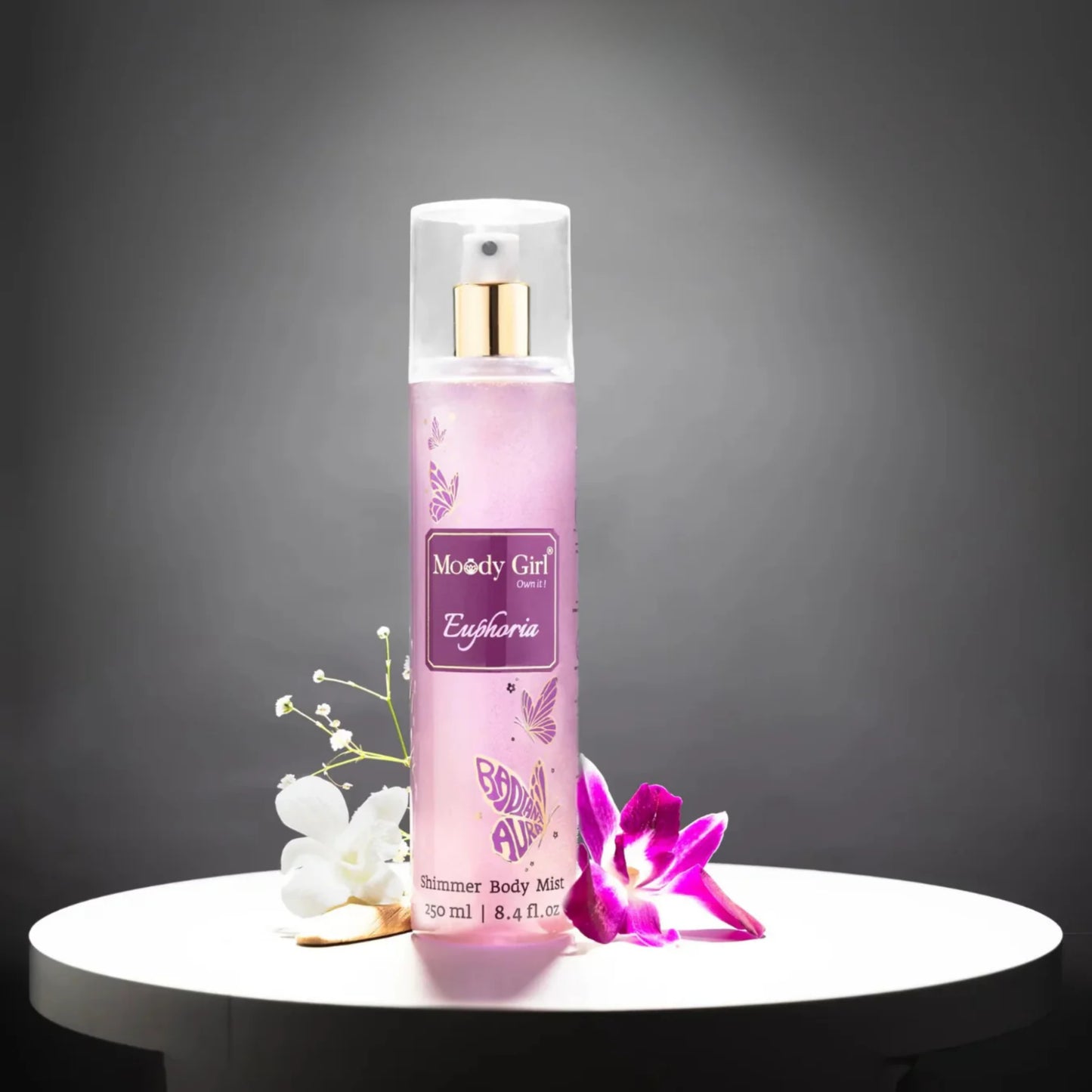 Pink body mist bottle with floral design on a dark background