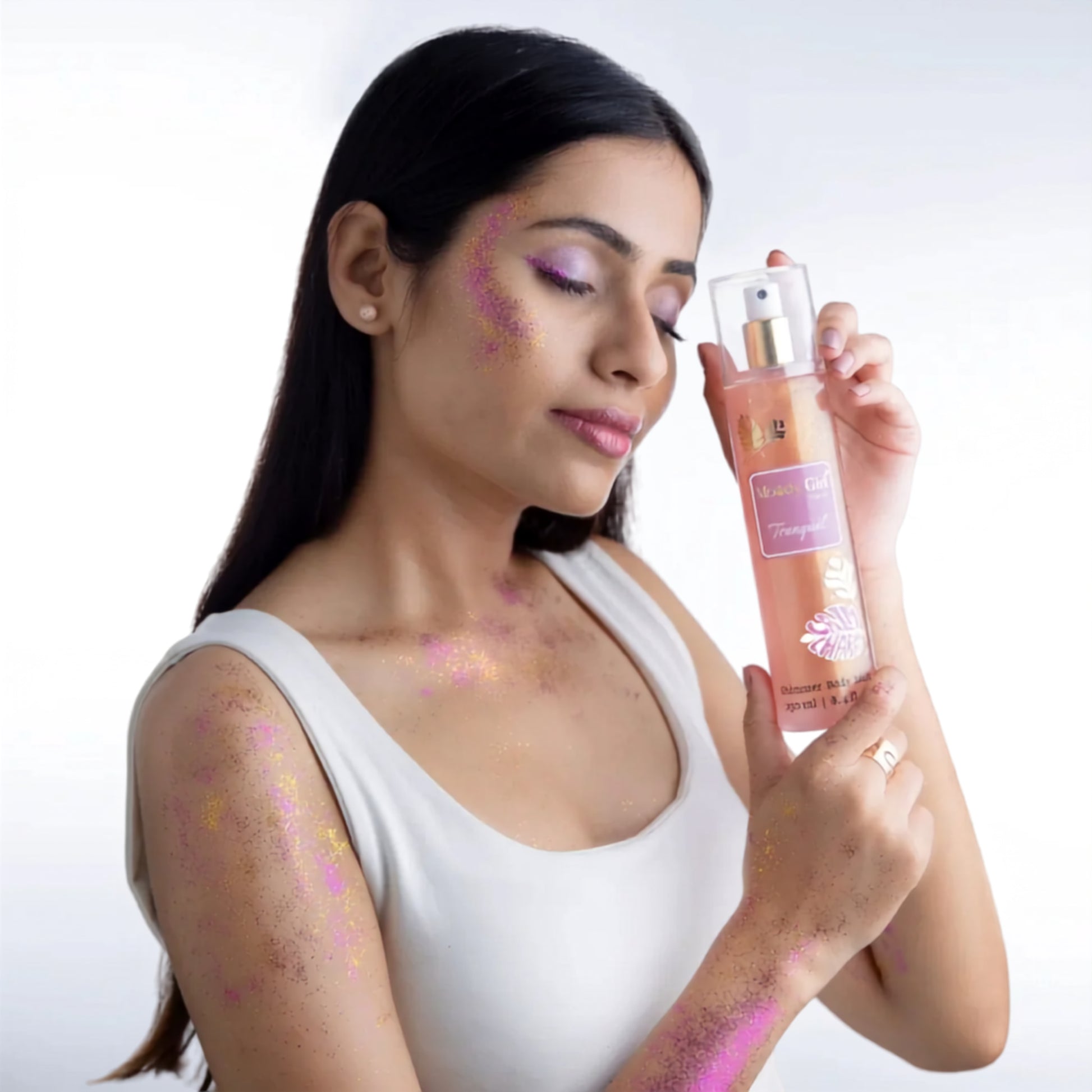 Woman holding a bottle of 'Bella' body spray with decorative elements on a white background