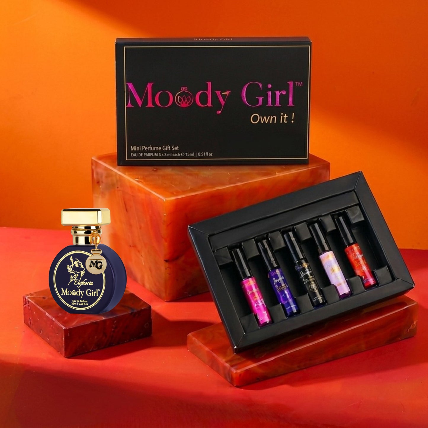 Moody Girl perfume set with a bottle and miniatures on an orange background
