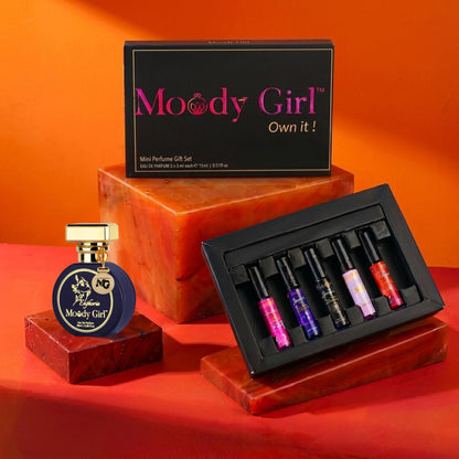 Moody Girl perfume set with a bottle and miniatures on an orange background