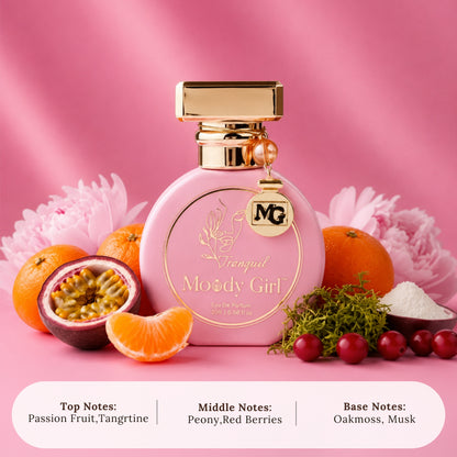 A pink perfume bottle labeled 'Vanguard Moody Girl' with gold detailing, styled with citrus fruits, a passion fruit, flowers, and berries on a pink background. Text at the bottom lists the scent notes.
