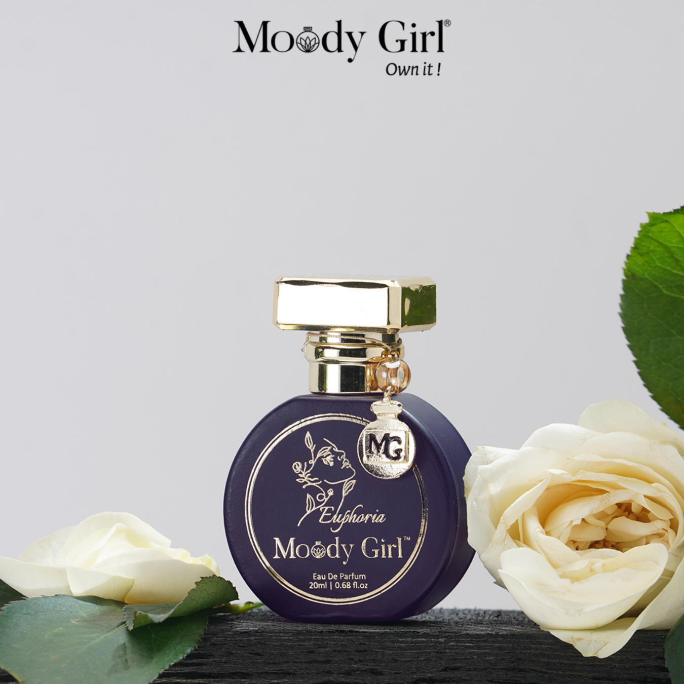 Moody Girl Euphoria perfume bottle with white roses on a light gray background