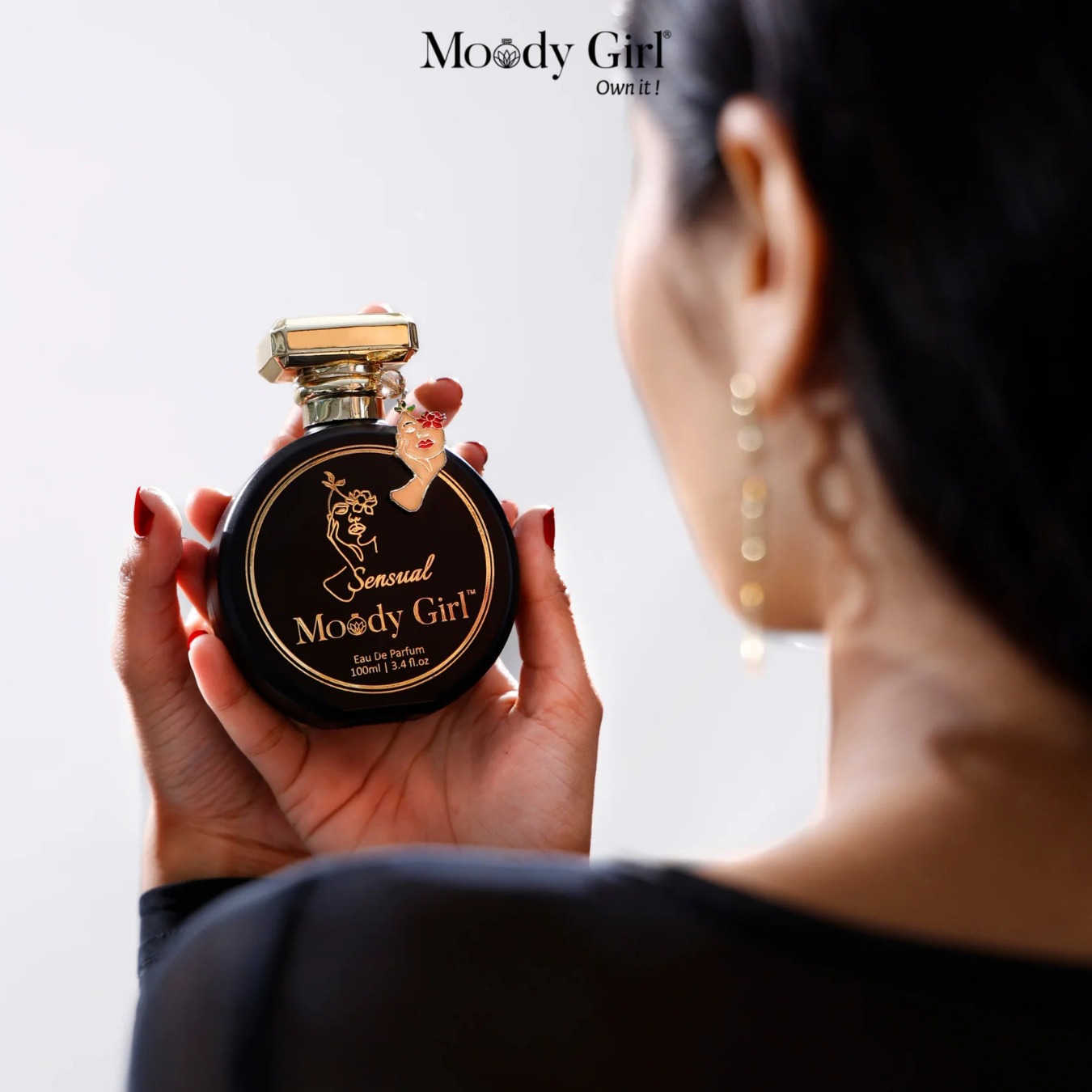 Person holding a Moody Girl perfume bottle with the brand name displayed.