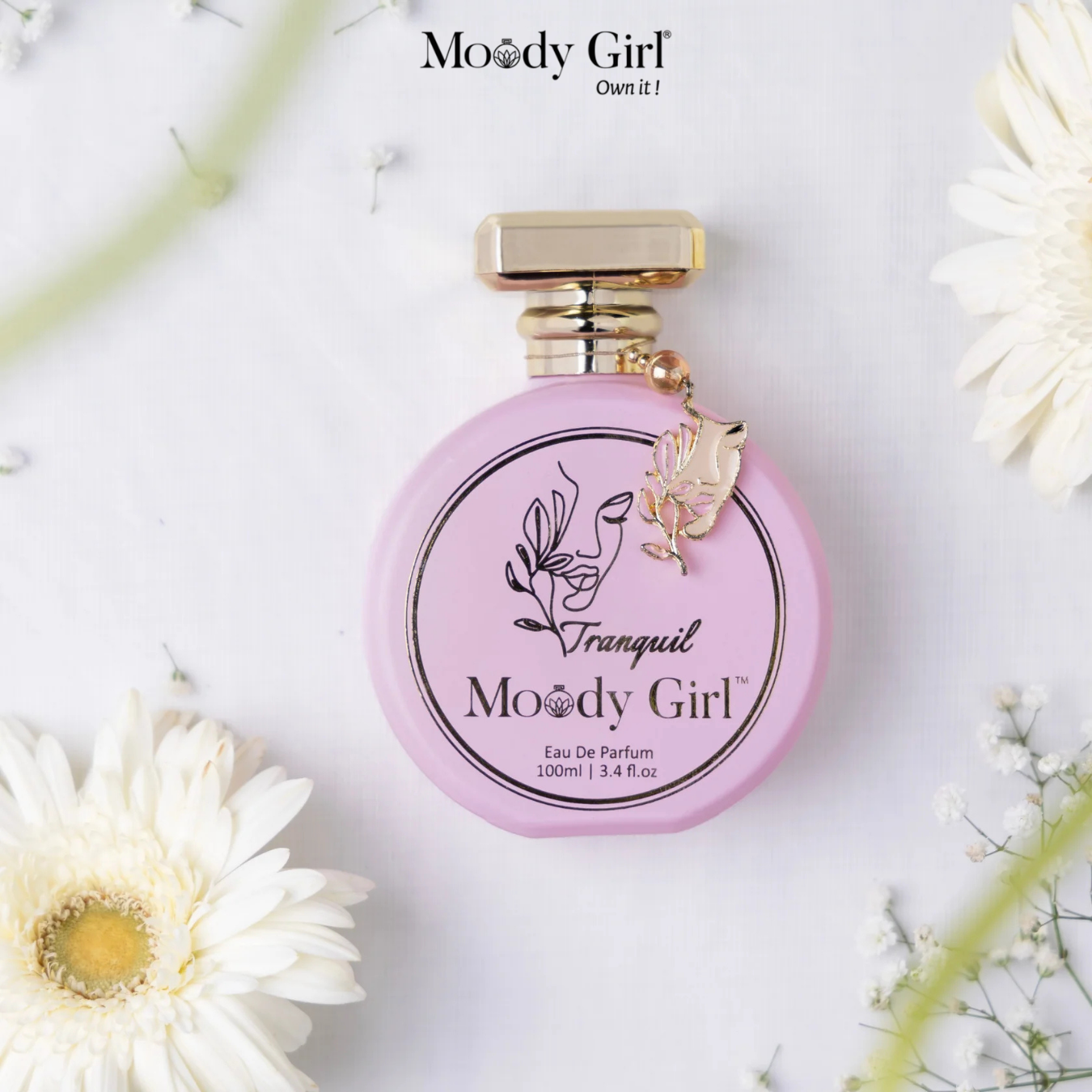 Pink perfume bottle with gold cap on a white background with flowers