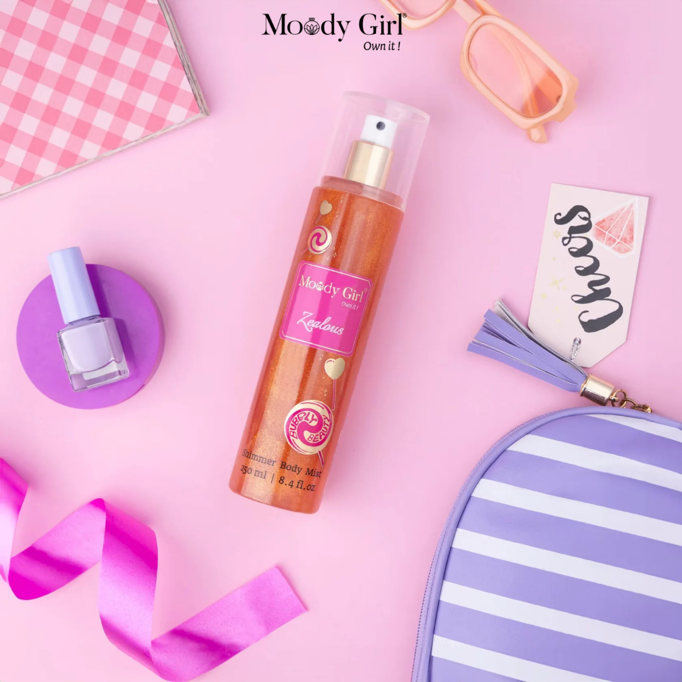 Moody Girl body mist bottle with accessories on a pink background