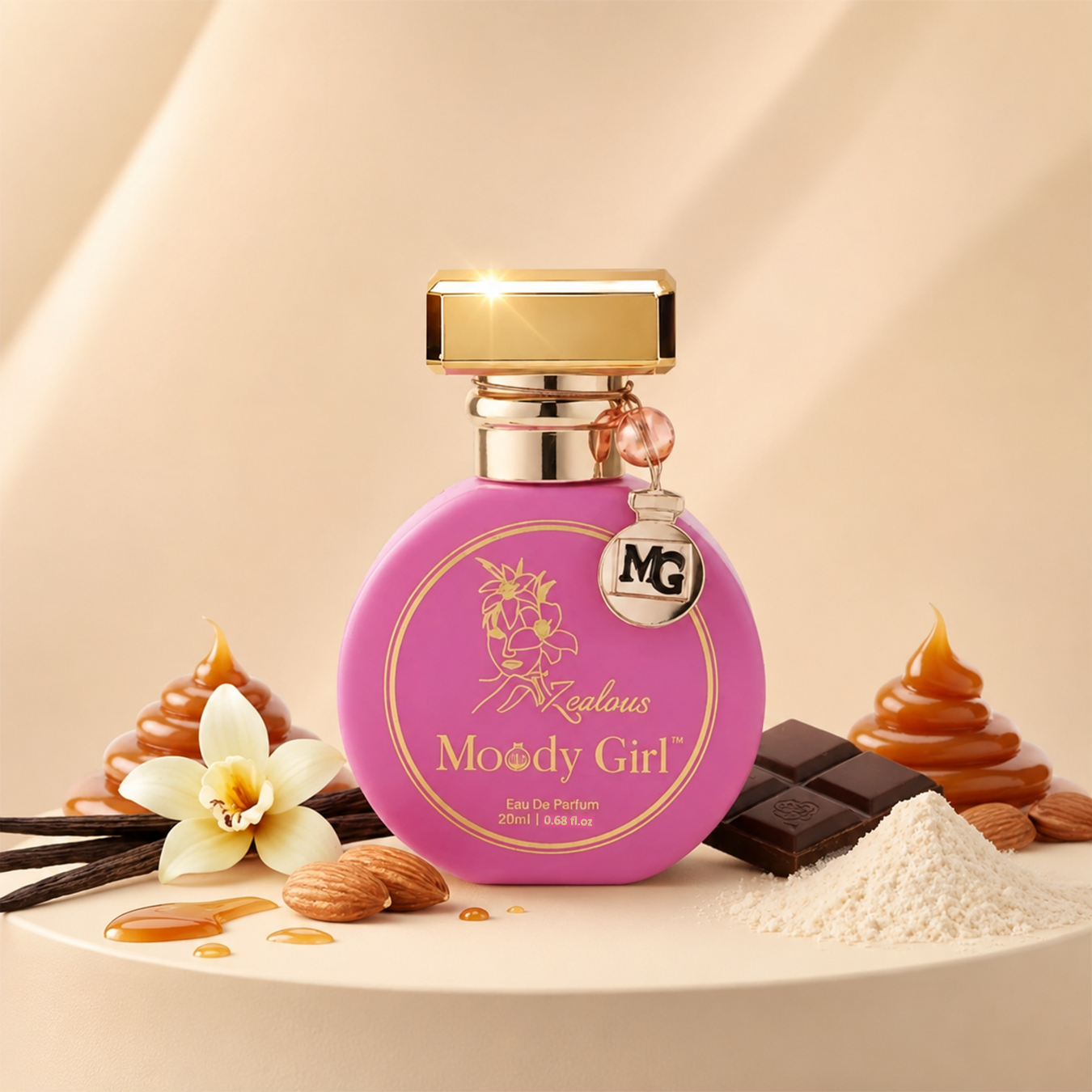 A round pink perfume bottle labeled 'Fascinating Moody Girl' with a gold cap, styled on a beige surface with caramel swirls, chocolate pieces, vanilla flower, almonds, and white powder.