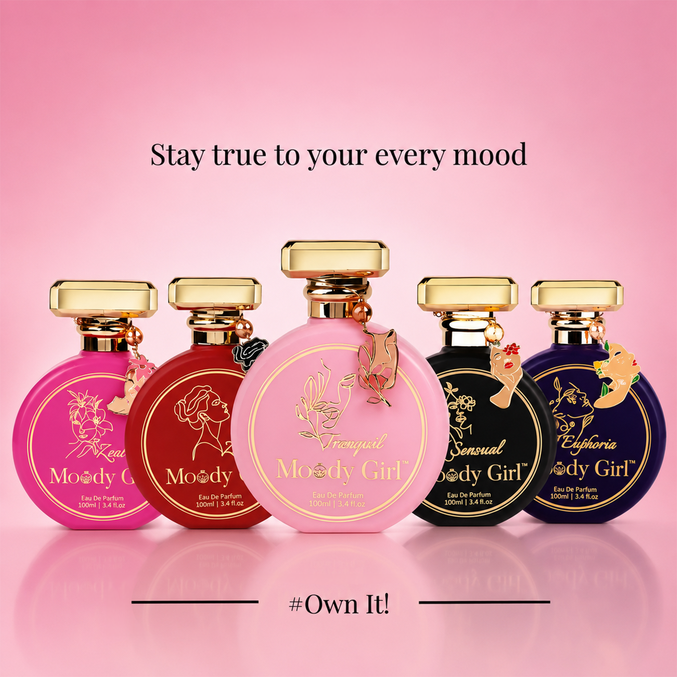 Five round perfume bottles labeled Moody Girl are arranged in a row on a pink gradient background with text reading 'Stay true to your every mood' and '#Own It!'. The bottles come in pink, red, light pink, black, and dark blue, each with gold caps and decorative labels.