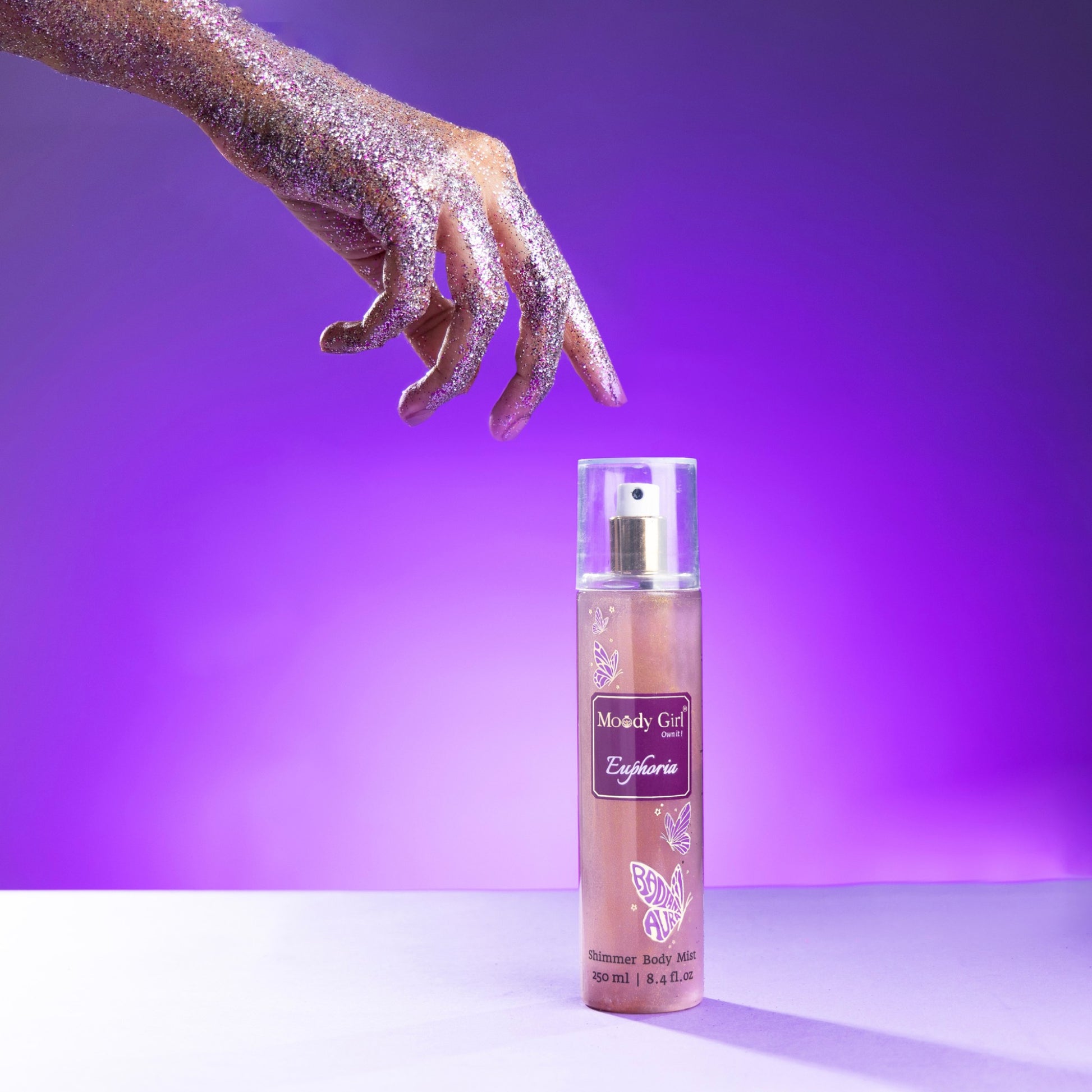 Spray bottle with glittery hand on a purple background