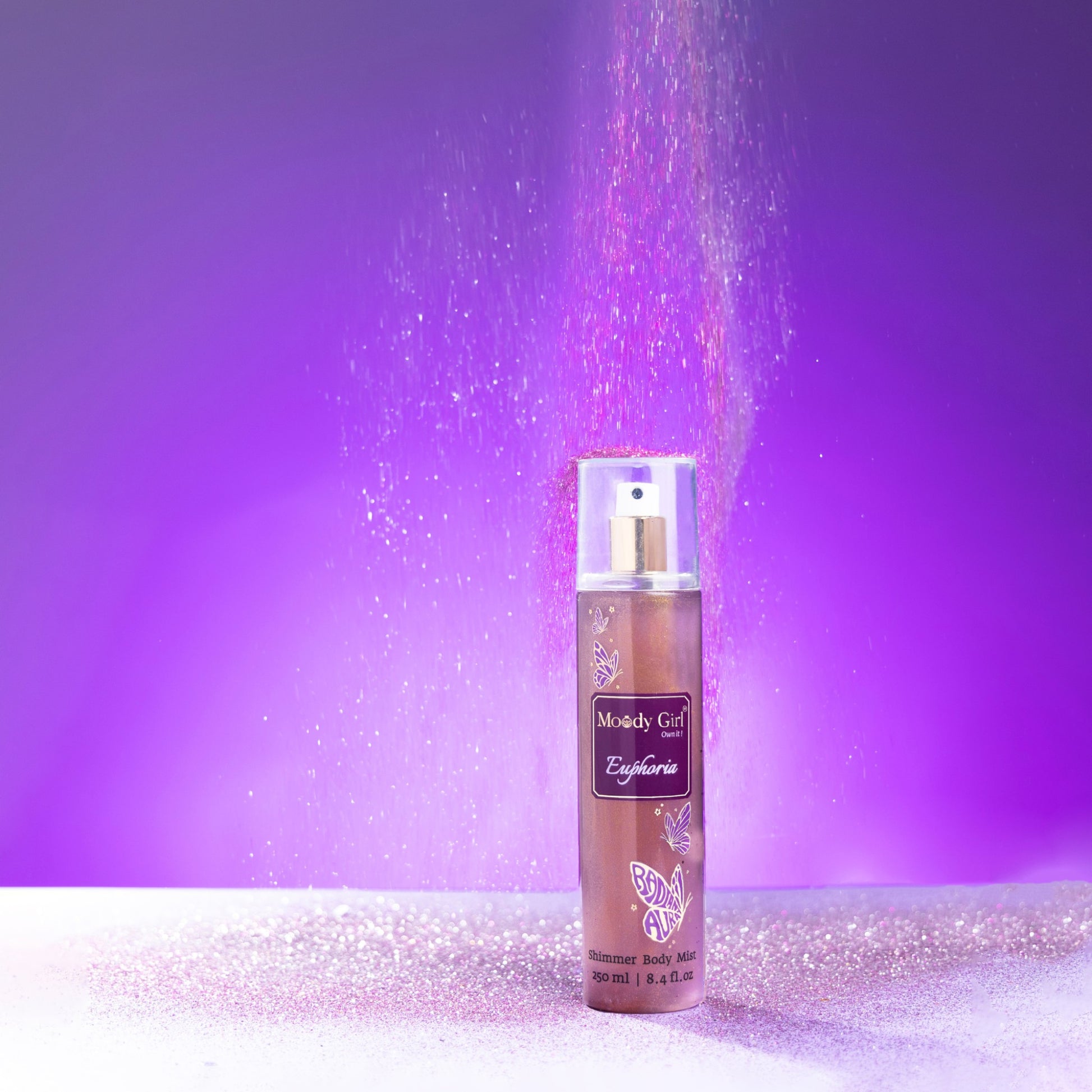 Body mist spray with glitter against a purple background