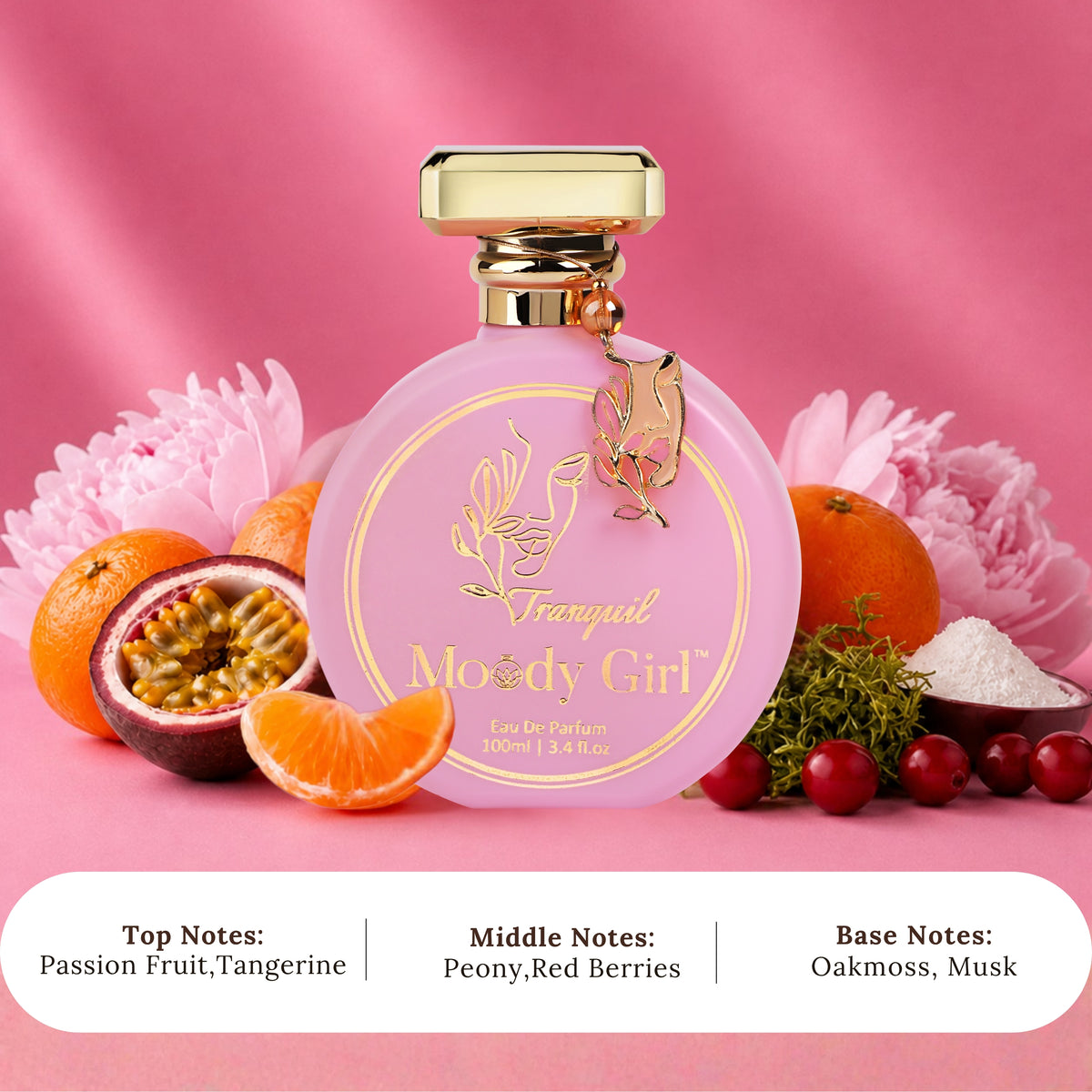 A pink perfume bottle labeled 'Tranquil Moody Girl' with a gold cap, styled with citrus fruits, flowers, and berries on a pink background. Text at the bottom lists the top, middle, and base notes.