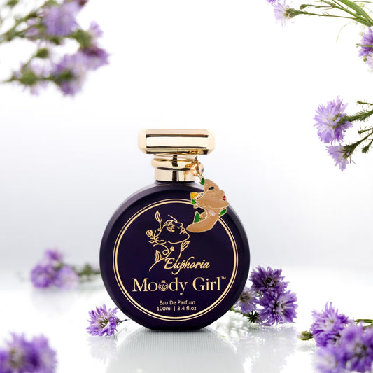 Moody Girl Euphoria perfume bottle with gold cap on a white background with purple flowers.