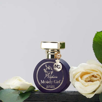 Perfume bottle labeled 'Moody Girl' with gold cap and white roses on a light gray background
