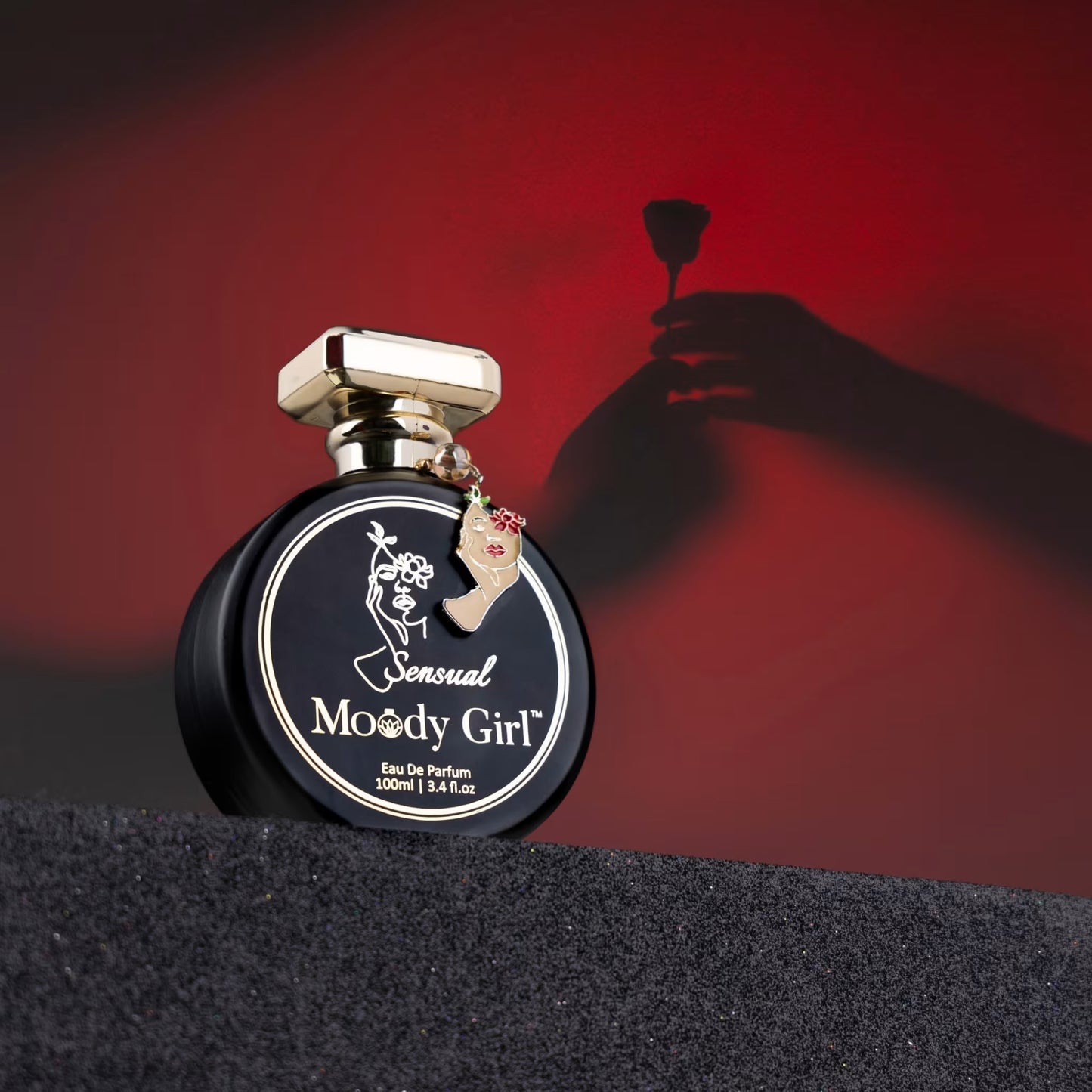Perfume bottle labeled 'Sensual Moody Girl' with a hand holding a flower against a red background
