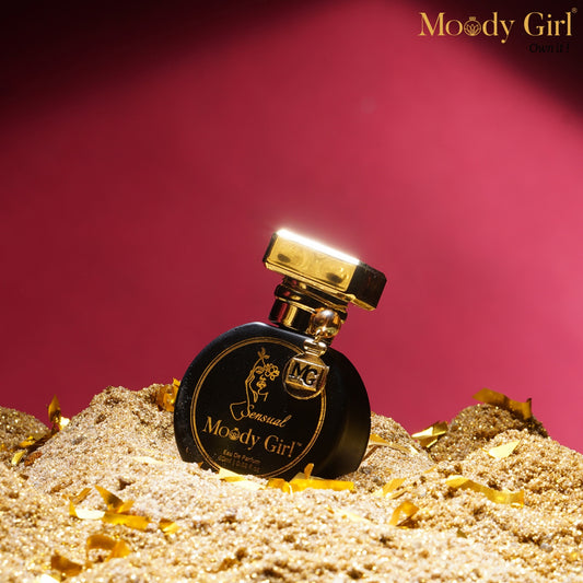 Moody Girl Sensual 20ml Perfume bottle labeled 'Moody Girl' on a sand-like surface with a pink background