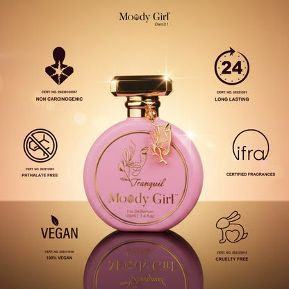 Pink perfume bottle with gold accents on a reflective surface, featuring Moody Girl branding and certification logos.