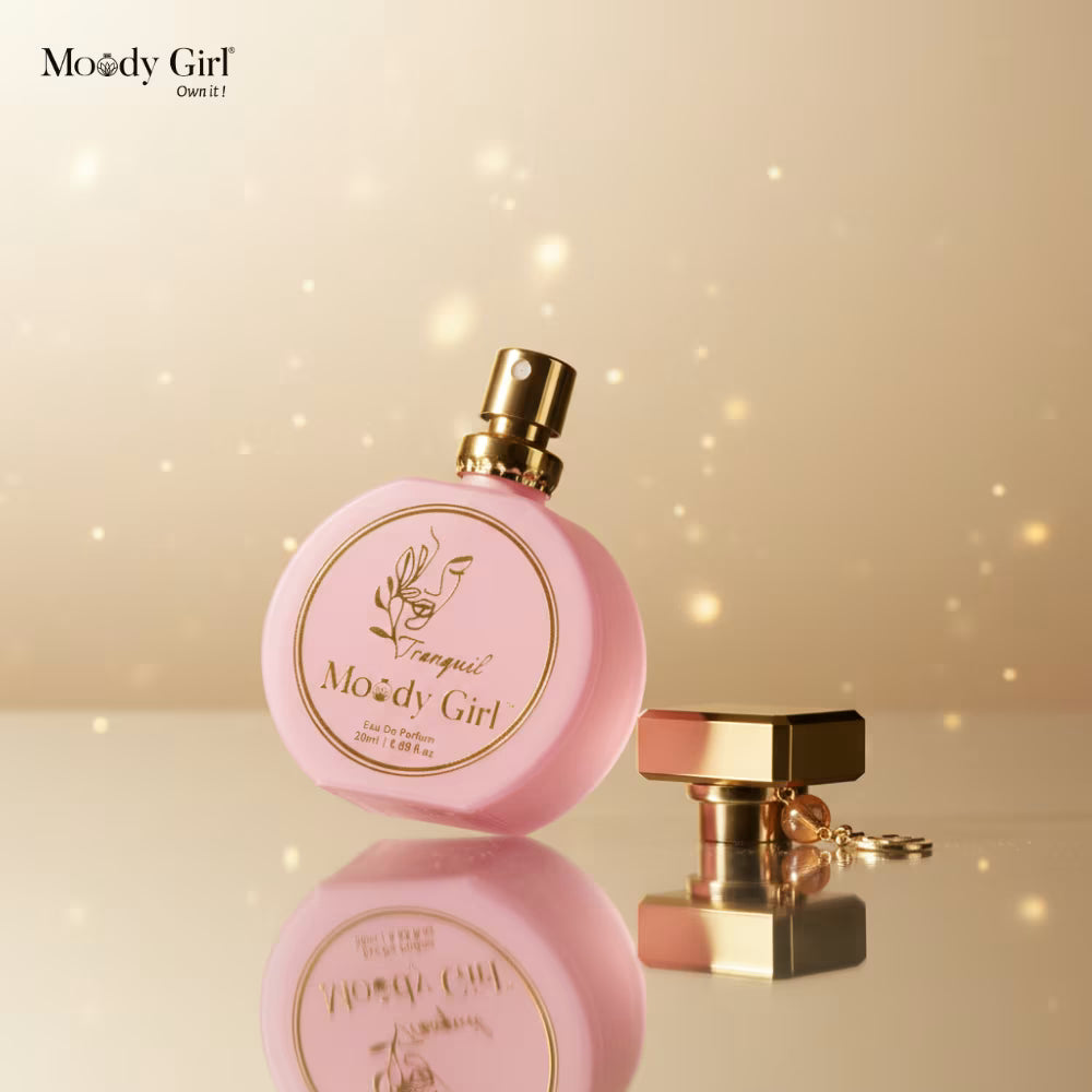 Pink perfume bottle with gold accents on a reflective surface and beige background