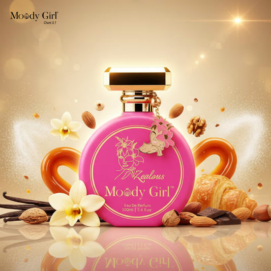Pink perfume bottle with gold cap on a reflective surface with flowers and pastries, branded 'Moody Girl'.