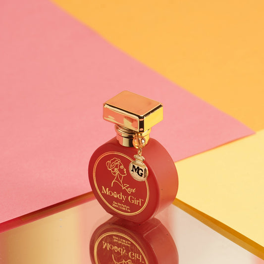 Moody Girl Zest 20ml Red perfume bottle with gold cap on a pink and yellow geometric background