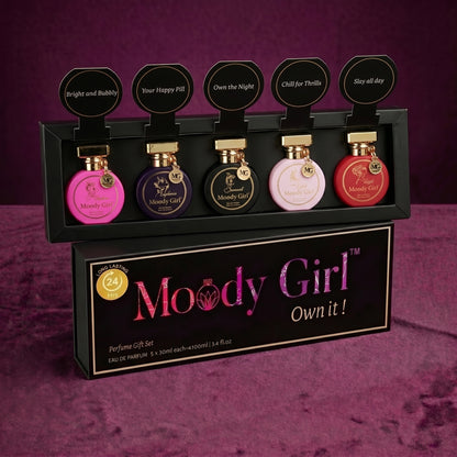 Set of Moody Girl perfumes in front of their packaging on a purple background