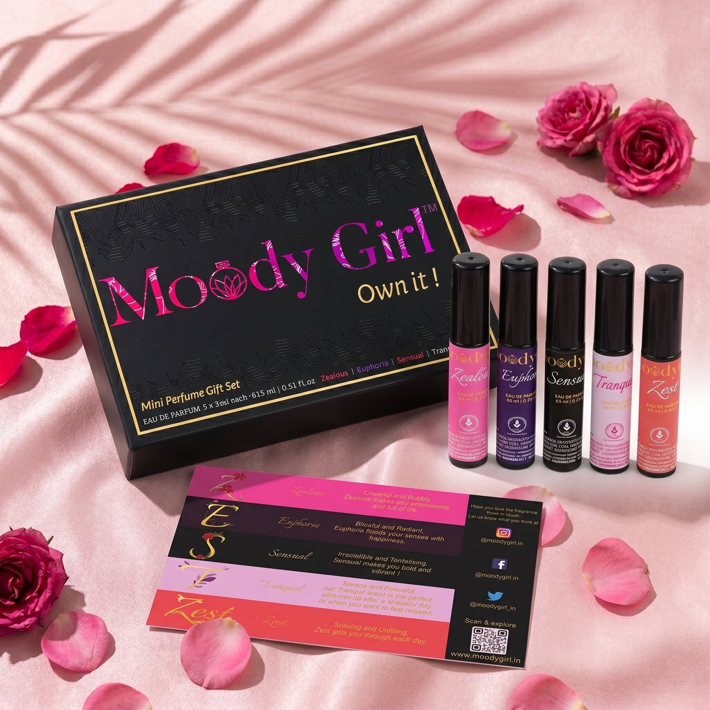 Moody Girl mini perfume gift set with six bottles and packaging on a pink background with roses and petals.