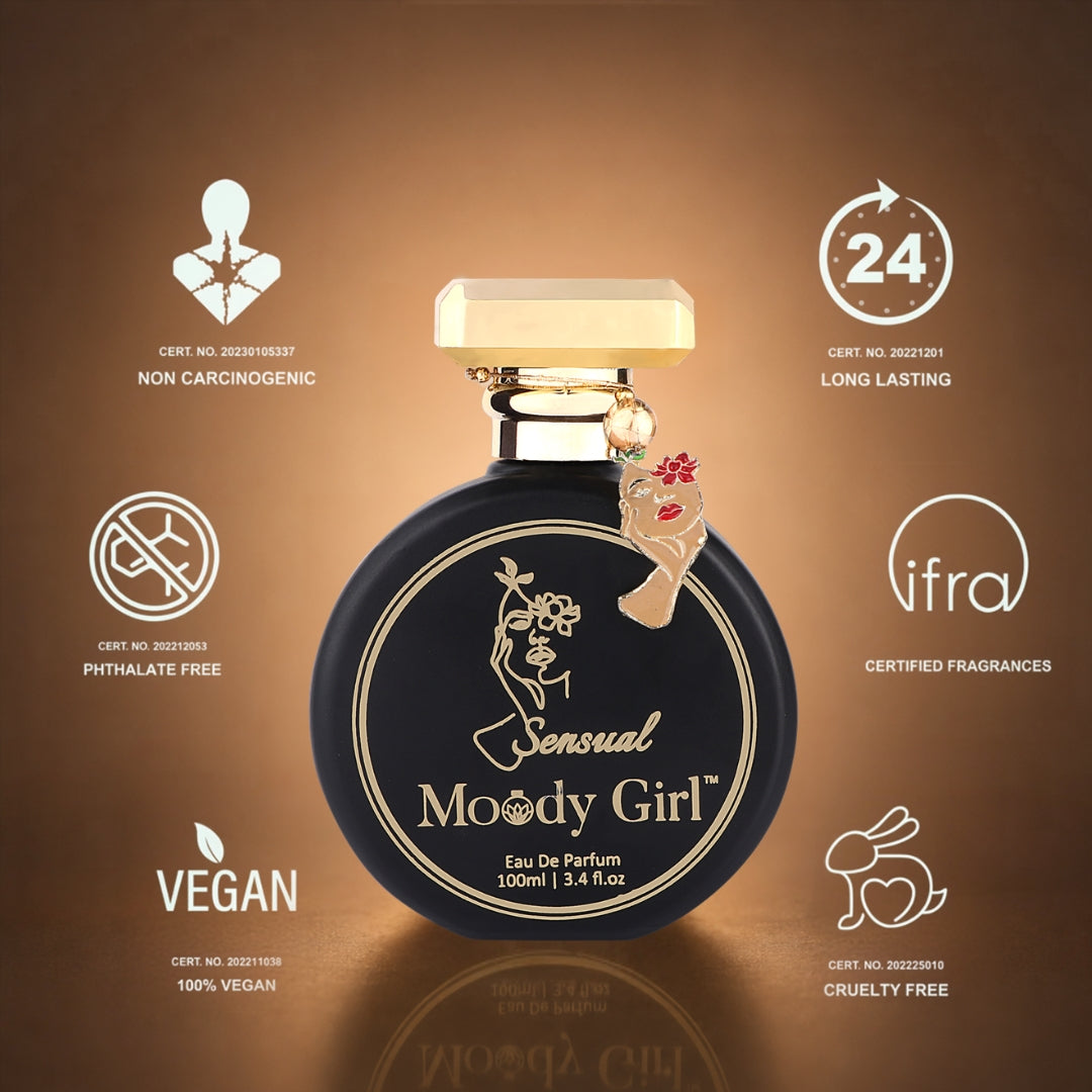 A round black perfume bottle labeled 'Sensual Moody Girl' with gold lettering and a small hanging cocktail charm, centered on a warm brown gradient background with certification icons around it.